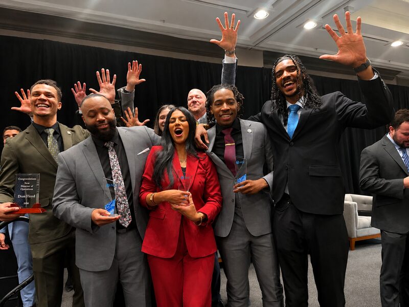 The Empire Acquisitions team celebrating on stage, several members holding awards