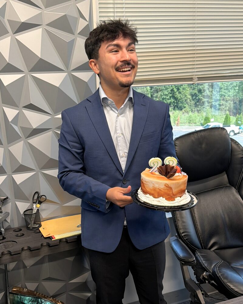 Connor Williams holding a birthday cake during an office celebration at Empire Acquisitions