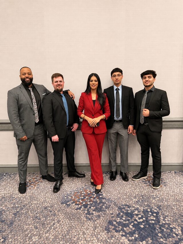 Five Empire Acquisitions team members in business attire at a corporate event