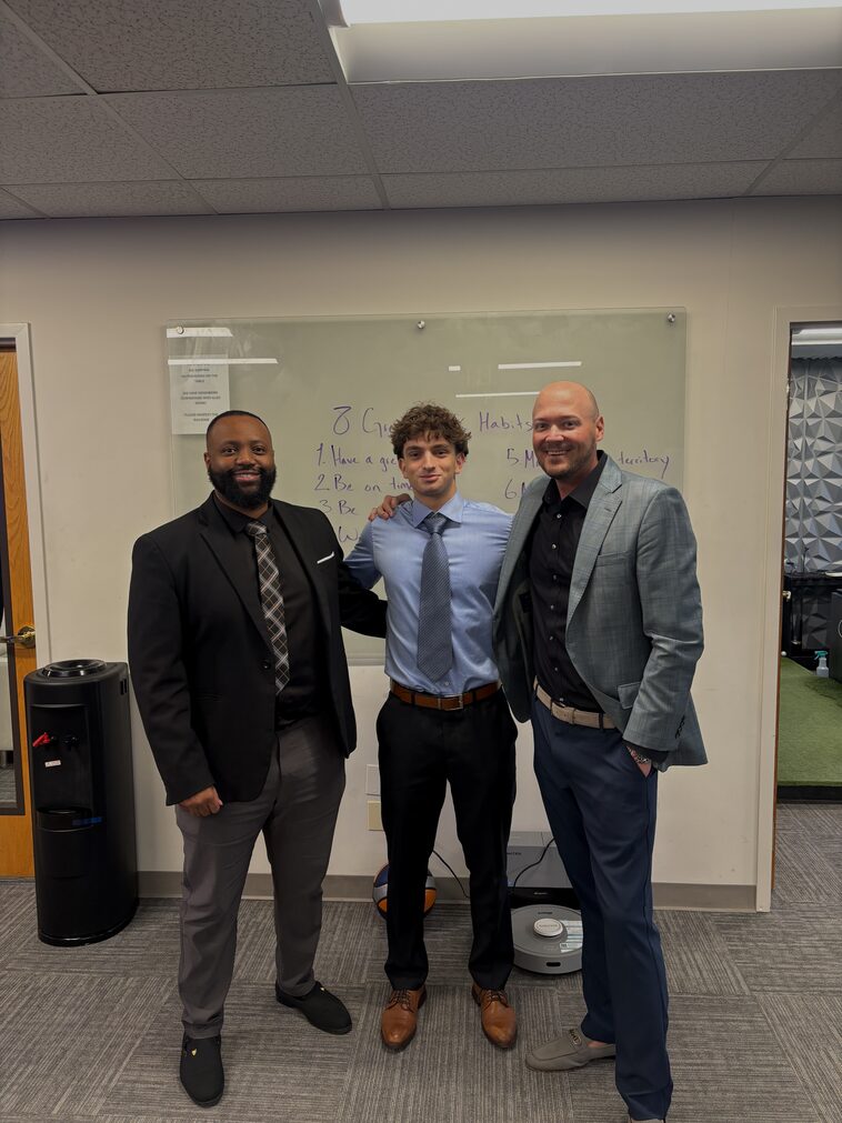 Three Empire Acquisitions representatives in the office in front of the goals whiteboard